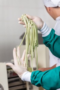 Cropped image of chef holding spaghetti pasta at commercial kitchen