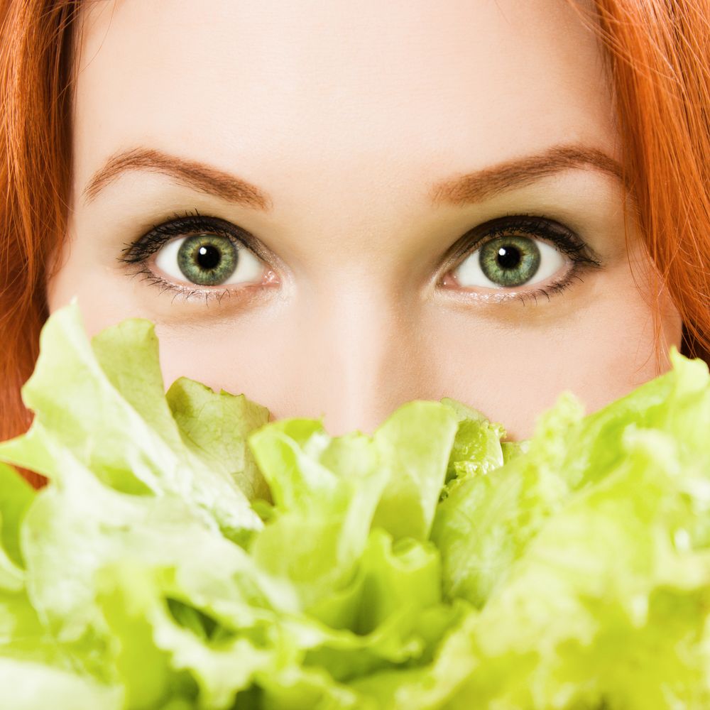 young beautiful woman eating salad close up