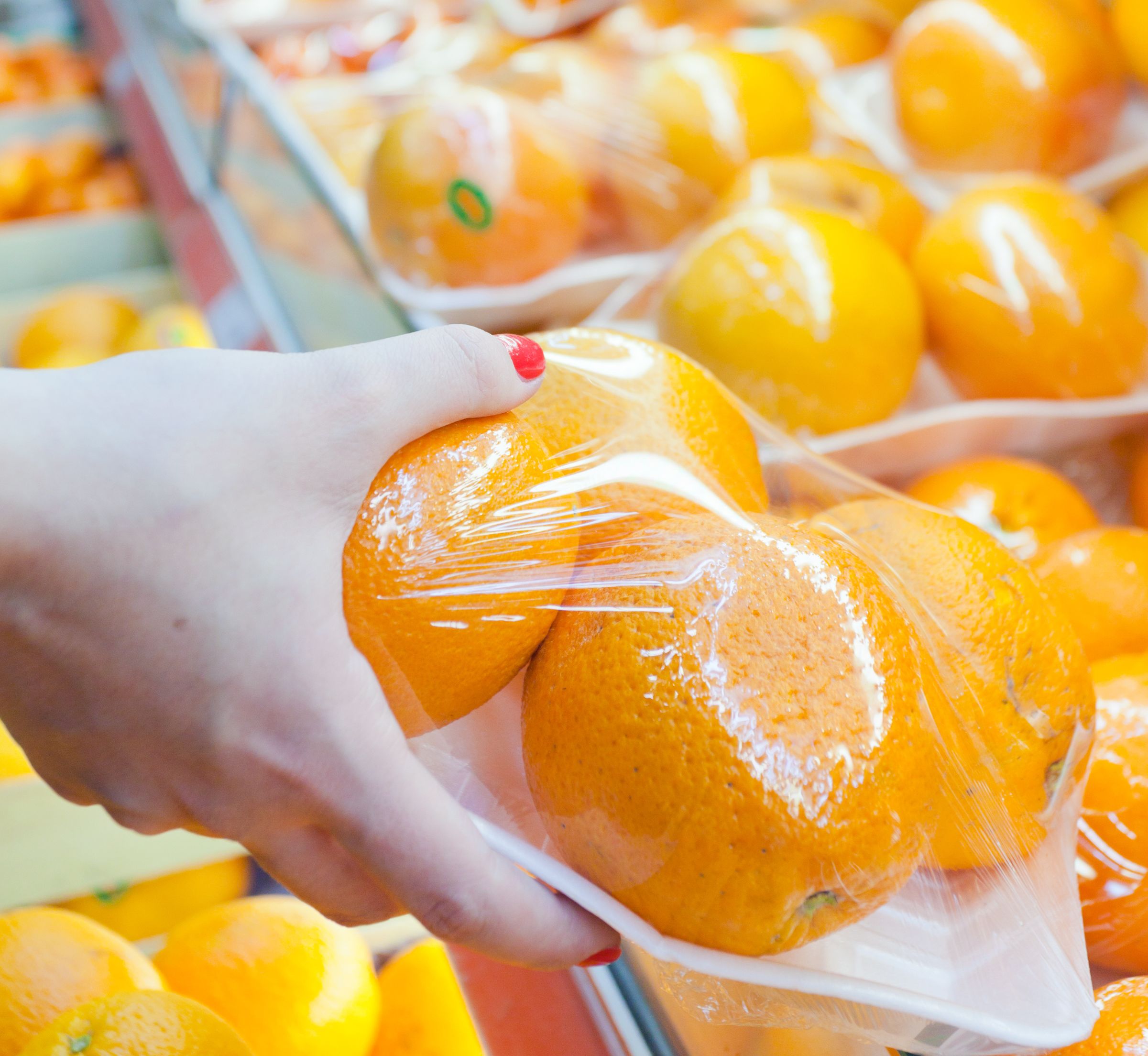 Image of packaged orange with woman hand in the supermarket